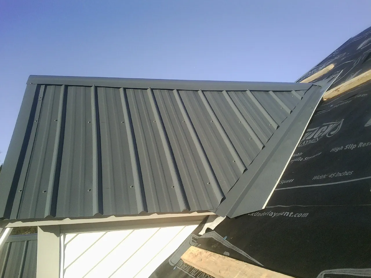 Gray metal roof panels going on over a garage gable in Grafton